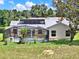Tranquil backyard with a pool, screening, and solar panels, surrounded by mature trees at 25400 Waterbrook Ct, Leesburg, FL 34748