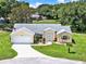Well-maintained single-story home featuring a lush green lawn, mature trees, and a two-car garage at 25400 Waterbrook Ct, Leesburg, FL 34748