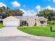 Charming home featuring a well-manicured lawn, mature landscaping, and a welcoming driveway at 25400 Waterbrook Ct, Leesburg, FL 34748