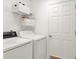 Bright laundry room featuring a white washer and dryer, wire shelving, and storage baskets at 25400 Waterbrook Ct, Leesburg, FL 34748