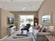 Cozy living room featuring neutral decor, vaulted ceilings, and sliding glass doors to the patio at 25400 Waterbrook Ct, Leesburg, FL 34748