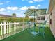 Private backyard patio with artificial turf, white picket fence and a charming outdoor seating set and umbrella at 2620 Persimmon Loop, The Villages, FL 32162