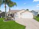 Charming home featuring a two-car garage, well-manicured lawn, and lush landscaping with swaying palm trees at 2620 Persimmon Loop, The Villages, FL 32162