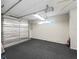 Spacious garage featuring a silver-insulated door, textured carpet, and fluorescent lighting at 2620 Persimmon Loop, The Villages, FL 32162