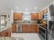 Well-lit kitchen featuring stainless steel appliances, granite countertops, wooden cabinetry, and modern tile flooring at 2620 Persimmon Loop, The Villages, FL 32162