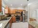 Bright kitchen featuring stainless steel appliances, granite counters, wooden cabinets, and a breakfast bar at 2620 Persimmon Loop, The Villages, FL 32162