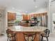 Open kitchen featuring stainless steel appliances, wooden cabinets, granite countertops, and a breakfast bar with seating at 2620 Persimmon Loop, The Villages, FL 32162
