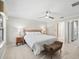Serene main bedroom with neutral decor, ceiling fan, and natural light, showcasing en-suite bathroom and closet access at 2620 Persimmon Loop, The Villages, FL 32162
