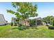 An angle view of the backyard featuring the screen porch, mature trees, and well-maintained landscaping at 2746 Edwards Ln, The Villages, FL 32162