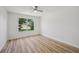 Bright bedroom with wood-look flooring, ceiling fan, and a view of the landscaped front yard at 2746 Edwards Ln, The Villages, FL 32162
