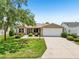 Charming single-story home with a well-maintained lawn, lush landscaping, and an attached two car garage at 2746 Edwards Ln, The Villages, FL 32162
