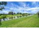 Lush backyard featuring a tranquil pond, green grass, and blue sky at 2880 Manor Downs, The Villages, FL 32162