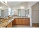 Bathroom featuring double sinks with granite countertops, large mirrors, and a walk-in shower at 2880 Manor Downs, The Villages, FL 32162