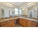 Bathroom vanity featuring double sinks, a granite countertop and large mirrors at 2880 Manor Downs, The Villages, FL 32162
