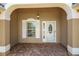 Close up of the front porch with brick flooring, white trim, and an elegant glass door at 2880 Manor Downs, The Villages, FL 32162