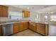 Well-lit kitchen showcasing granite counters, wooden cabinets, and stainless steel dishwasher at 2880 Manor Downs, The Villages, FL 32162