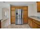 Kitchen with stainless steel refrigerator and natural wood cabinets and granite countertops at 2880 Manor Downs, The Villages, FL 32162