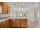Spacious kitchen features wood cabinetry and a granite countertop island bar with views into the dining area at 2880 Manor Downs, The Villages, FL 32162