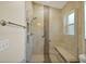 Walk-in shower featuring beige tiles, a built-in bench, a window, and a glass partition at 2880 Manor Downs, The Villages, FL 32162