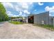 Exterior view of a metal building with a gravel parking area, landscaping, and roll up doors at 32511 County Road 437, Sorrento, FL 32776