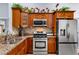 Kitchen featuring granite countertops, stainless steel appliances, and wood cabinets with floral accents at 3309 Paisley Cir, Orlando, FL 32817
