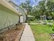 Green house exterior, showing a pathway to an open door, plants and backyard at 4207 Bair Ave, Fruitland Park, FL 34731