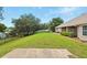 Green, well-manicured back yard with a concrete patio, partial fence line and mature trees at 4401 Abaco Dr, Tavares, FL 32778