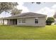 Back of house with a well maintained lawn and mature trees at 5005 County Road 125B1, Wildwood, FL 34785