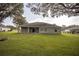Back of the house with a covered patio and a fire pit in the manicured lawn at 5005 County Road 125B1, Wildwood, FL 34785
