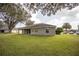 Back of house with a well maintained lawn and mature trees at 5005 County Road 125B1, Wildwood, FL 34785