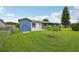 Backyard with small storage shed, concrete patio and screened-in porch surrounded by lush greenery at 550 Floral Dr, Kissimmee, FL 34743