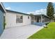 Exterior view of the house featuring a concrete patio and screened-in porch with green lawn at 550 Floral Dr, Kissimmee, FL 34743