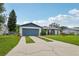 Well-maintained single-story home showcasing a concrete driveway, blue garage door, and lush green lawn at 550 Floral Dr, Kissimmee, FL 34743