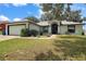 Charming single-story home featuring a well-manicured lawn, landscaping, and an attached two car garage at 6001 Pine Bluff Ln, Mascotte, FL 34753