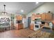 Well-lit kitchen featuring wood cabinets, white appliances, granite countertops, and tile flooring at 6001 Pine Bluff Ln, Mascotte, FL 34753