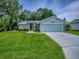 Charming single-story home with a well-manicured lawn, blue siding, and an attached two-car garage at 627 Timbercrest Dr, Leesburg, FL 34748