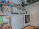 Functional laundry room with modern washer and dryer, storage shelves, and a utility sink at 627 Timbercrest Dr, Leesburg, FL 34748