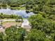 Stunning aerial view showcasing a home, pool, and lush greenery by a serene lake under a blue sky at 628 Drew Ave, Clermont, FL 34711