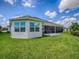 Backyard view highlighting screened-in lanai, well-kept lawn, and privacy at 6295 Danielson Loop, The Villages, FL 32163
