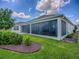 Backyard view showing the large screened-in lanai and lush landscaping at 6295 Danielson Loop, The Villages, FL 32163