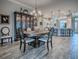 An open dining room boasts a chandelier and complements a large china cabinet and wood floors at 6295 Danielson Loop, The Villages, FL 32163
