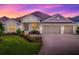 Charming home exterior with well-manicured lawn, mature landscaping, and three-car garage at 6295 Danielson Loop, The Villages, FL 32163