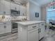 An open kitchen features an island, white countertops, shaker cabinets, and stainless steel appliances at 6295 Danielson Loop, The Villages, FL 32163