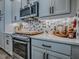 A contemporary kitchen features white countertops, stainless appliances, mosaic backsplash, and shaker-style cabinets at 6295 Danielson Loop, The Villages, FL 32163