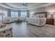 A spacious primary bedroom suite offers lots of natural light, a sitting area, and wood-look flooring at 6295 Danielson Loop, The Villages, FL 32163