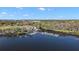 Aerial view showcasing a marina with boats, surrounded by lush trees, and the city in the distance at 6616 Tuscawilla Dr, Leesburg, FL 34748