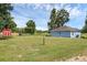 Spacious backyard featuring a blue home, a red shed, and large green space at 8634 Garden Way Rd, Groveland, FL 34736