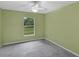 Empty bedroom with green walls, ceiling fan, and a window overlooking the yard at 8634 Garden Way Rd, Groveland, FL 34736