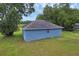 A charming blue home with a dark roof surrounded by lush greenery and a clear blue sky at 8634 Garden Way Rd, Groveland, FL 34736