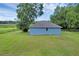 A well-maintained blue single-story home with a grey roof, set on a lush green lawn at 8634 Garden Way Rd, Groveland, FL 34736